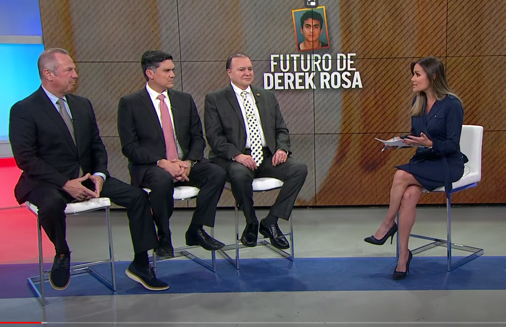 A group of men and women, including Derek Rosa, sit on a TV set.